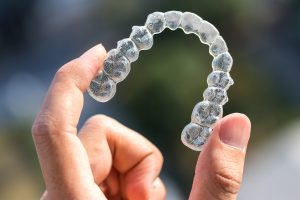 Invisalign tray being held between two fingers.