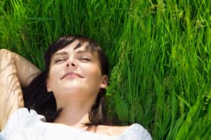 A young woman sleeping in grass after a relaxing dental treatment in Oceanside.